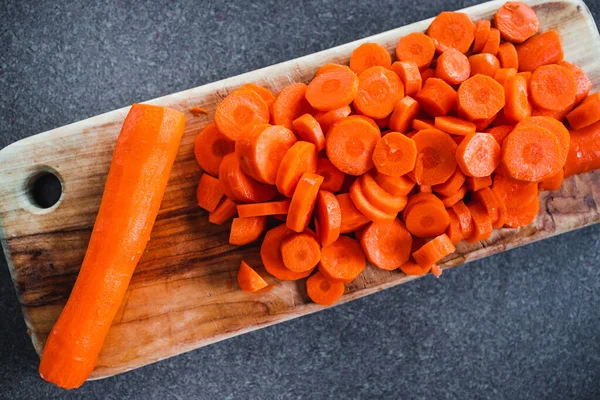 Tahta doğrama tahtasının üzerinde taze havuçların dilimlendiği yakın plan çekimler, basit, sağlıklı malzemeler kavramı.