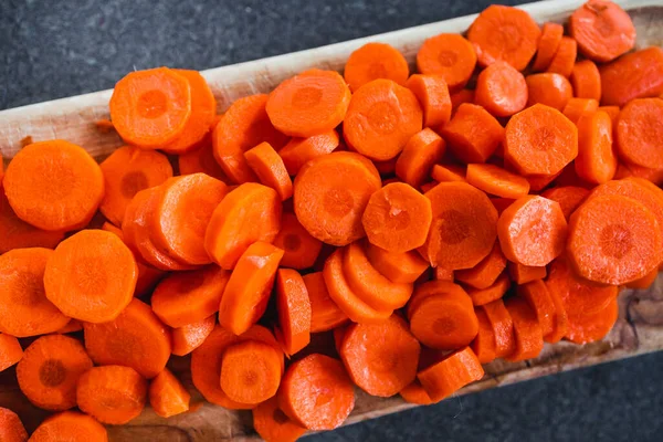 Tahta doğrama tahtasının üzerinde taze havuçların dilimlendiği yakın plan çekimler, basit, sağlıklı malzemeler kavramı.