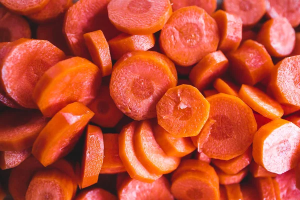 Tahta doğrama tahtasının üzerinde taze havuçların dilimlendiği yakın plan çekimler, basit, sağlıklı malzemeler kavramı.