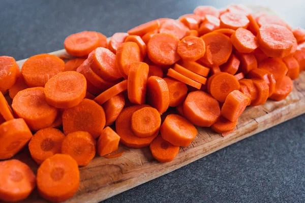 Tahta doğrama tahtasının üzerinde taze havuçların dilimlendiği yakın plan çekimler, basit, sağlıklı malzemeler kavramı.