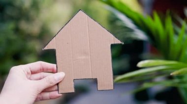 Arka bahçedeki Bokeh 'in önünde el ele tutuşan ev ikonu, ev ve emlak piyasası ya da rüya ev ya da aile hayatı kavramı