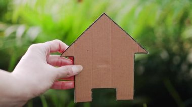 Evin dış ve arka bahçesinde el ele tutuşan ev ikonu Bokeh, ev ve emlak piyasası ya da rüya evi ya da aile hayatı kavramı