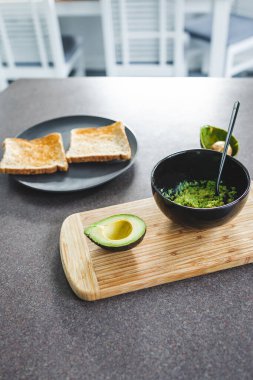 Yanında yarım avokado ve guacamole ile temel bitkisel ezilmiş avokado tostu ve yemek odası bokeh, sağlıklı vegan yemek tarifleri.