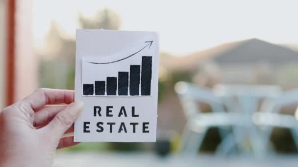 Hand Holding Real Estate Sign Graph Showing Stats Going Front — ストック動画