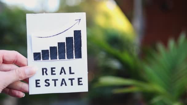 Hand Holding Real Estate Sign Graph Showing Stats Going Front — Video