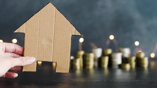 房地产价格上涨或抵押贷款利率上升的概念形象 纸板屋前面堆放着一堆堆神灯作为背景的硬币 — 图库视频影像