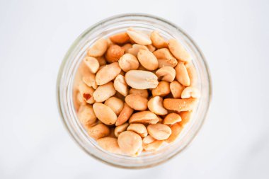 Beyaz mermer arka planda cam fıstık kavanozu, doğal sağlıklı kiler malzemeleri.