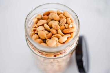 Beyaz mermer arka planda cam fıstık kavanozu, doğal sağlıklı kiler malzemeleri.