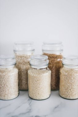 glass jar with rice of different varieties including jasmine basmati arborio sushi and brown rice, healthy pantry ingredients and staples