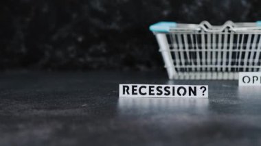 recession or opportunity texts wth shopping basket on dark background with focus switching between the two