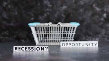 recession or opportunity texts wth shopping basket on dark background with focus switching between the two