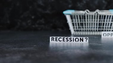 recession or opportunity texts wth shopping basket on dark background with focus switching between the two