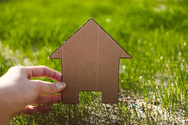 green home and construction industry, house icon on green grass lawn under the sun with bokeh