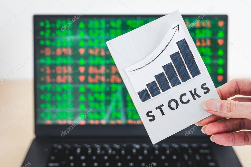 concept of trading stocks online, chart with Stock text in front of computer screen with financal markets results