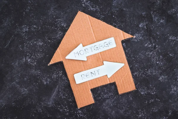 house icon with mortgage or rent signs pointing in opposite directions on dark background, concept of real estate affordability and property market