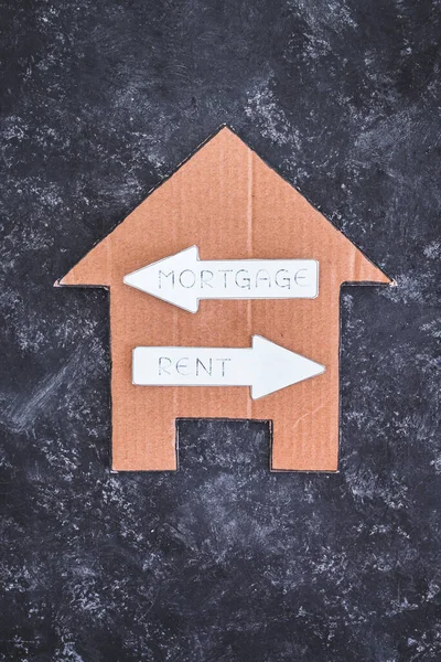 house icon with mortgage or rent signs pointing in opposite directions on dark background, concept of real estate affordability and property market