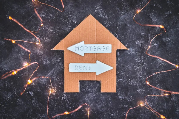 house icon with mortgage or rent signs pointing in opposite directions on dark background with LED lights, concept of real estate affordability and property market