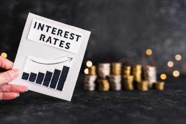 interest rates text and graph showing stats going up in front of stacks on coins and lights, concept of global economy after the covid-19 pandemic
