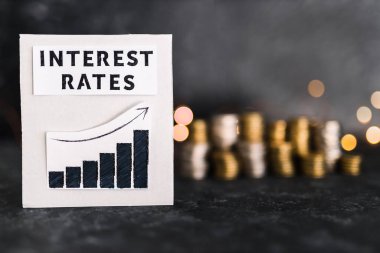 interest rates text and graph showing stats going up in front of stacks on coins and lights, concept of global economy after the covid-19 pandemic