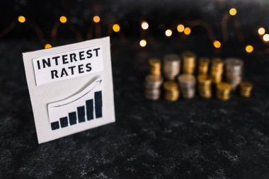 interest rates text and graph showing stats going up in front of stacks on coins and lights, concept of global economy after the covid-19 pandemic