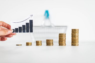 rising inflation graph in front of shopping basket and growing stacks of coins representing increasingly expensive prices, concept of global economy struggling after the covid-19 pandemic