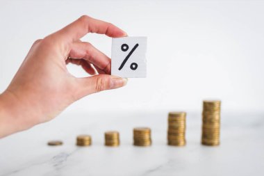 interest rates for loans and mortgages going up conceptual image, percentage symbol with growing stacks of coins representing increasingly expensive cost of financing