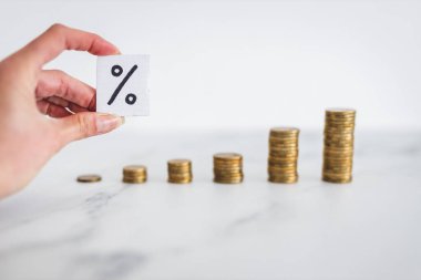 interest rates for loans and mortgages going up conceptual image, percentage symbol with growing stacks of coins representing increasingly expensive cost of financing