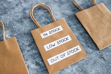 In stock, low stock and out of stock texts on top of shopping bags, concept of supply chain shortages and delays after the covid-19 global pandemic