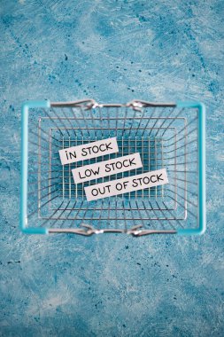 In stock, low stock and out of stock texts inside of empty shopping basket, concept of supply chain shortages and delays after the covid-19 global pandemic