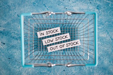 In stock, low stock and out of stock texts inside of empty shopping basket, concept of supply chain shortages and delays after the covid-19 global pandemic