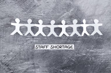 staff shortages and business struggling after the pandemic conceptual image, peper people chain with text on gray background