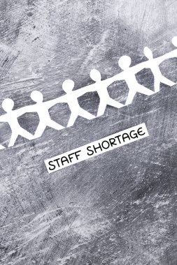 staff shortages and business struggling after the pandemic conceptual image, peper people chain with text on gray background