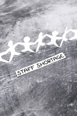 staff shortages and business struggling after the pandemic conceptual image, peper people chain with text on gray background