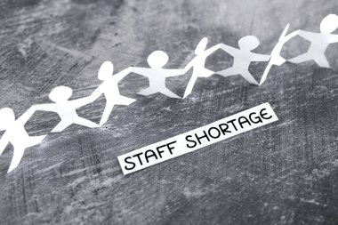 staff shortages and business struggling after the pandemic conceptual image, peper people chain with text on gray background