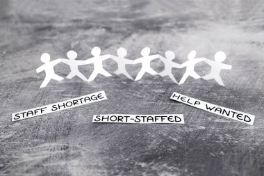 staff shortages and business struggling after the pandemic conceptual image, peper people chain with text on gray background