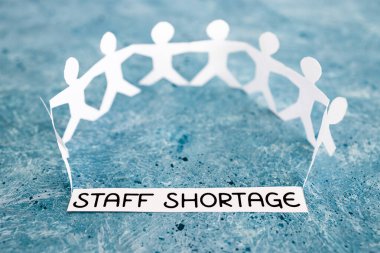 staff shortages and business struggling after the pandemic conceptual image, peper people chain with text on blue background