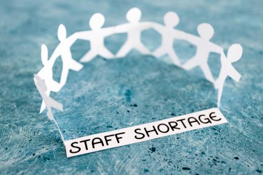 staff shortages and business struggling after the pandemic conceptual image, peper people chain with text on blue background