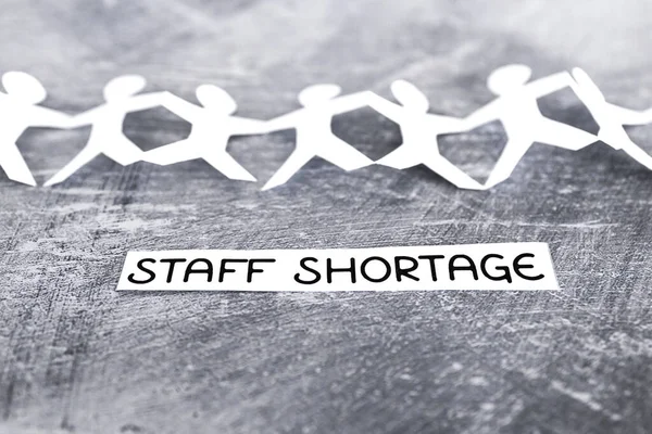 staff shortages and business struggling after the pandemic conceptual image, peper people chain with text on gray background