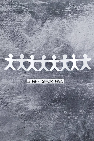 staff shortages and business struggling after the pandemic conceptual image, peper people chain with text on gray background