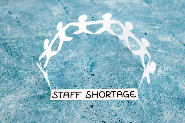 staff shortages and business struggling after the pandemic conceptual image, peper people chain with text on blue background