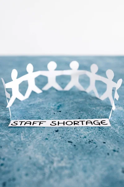 staff shortages and business struggling after the pandemic conceptual image, peper people chain with text on blue background