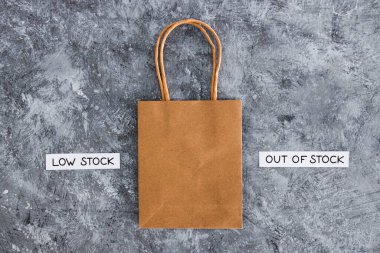 Low stock and out of stock text next to empty shopping bag, concept of supply chain shortages and delays after the covid-19 global pandemic