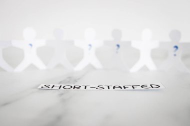 staff shortages and hiring personnel conceptual image, paper people chain with question marks on some people symbol of positions to be filled
