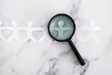 staff shortages and hiring personnel conceptual image, paper people chain with magnifying glass analysing them