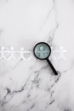 staff shortages and hiring personnel conceptual image, paper people chain with magnifying glass analysing them