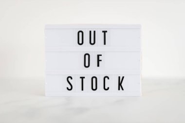 Out of stock text on lightbox on minimalistic white marble background, concept of supply chain shortages and delays after the covid-19 global pandemic