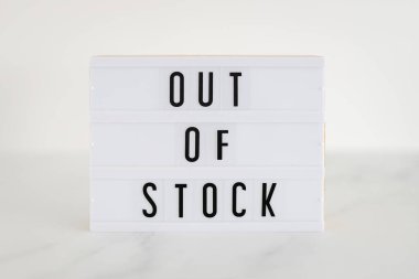 Out of stock text on lightbox on minimalistic white marble background, concept of supply chain shortages and delays after the covid-19 global pandemic