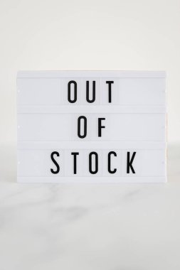 Out of stock text on lightbox on minimalistic white marble background, concept of supply chain shortages and delays after the covid-19 global pandemic