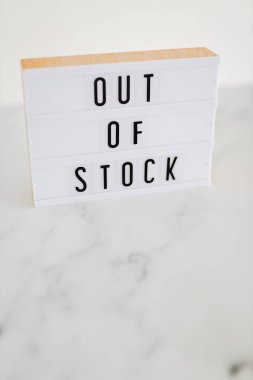 Out of stock text on lightbox on minimalistic white marble background, concept of supply chain shortages and delays after the covid-19 global pandemic