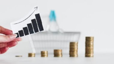 rising inflation graph in front of shopping basket and growing stacks of coins representing increasingly expensive prices, concept of global economy struggling after the covid-19 pandemic